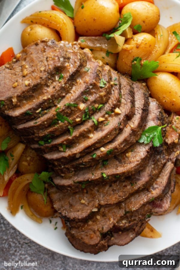 Melt in Your Mouth Slow Cooker Pot Roast 3 Overhead view of a perfectly sliced slow cooker pot roast with vegetables and gravy on a white plate.