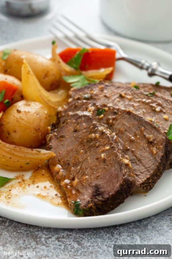 Melt in Your Mouth Slow Cooker Pot Roast 5 Perfectly sliced pot roast with luscious gravy on a white plate, ready to serve.