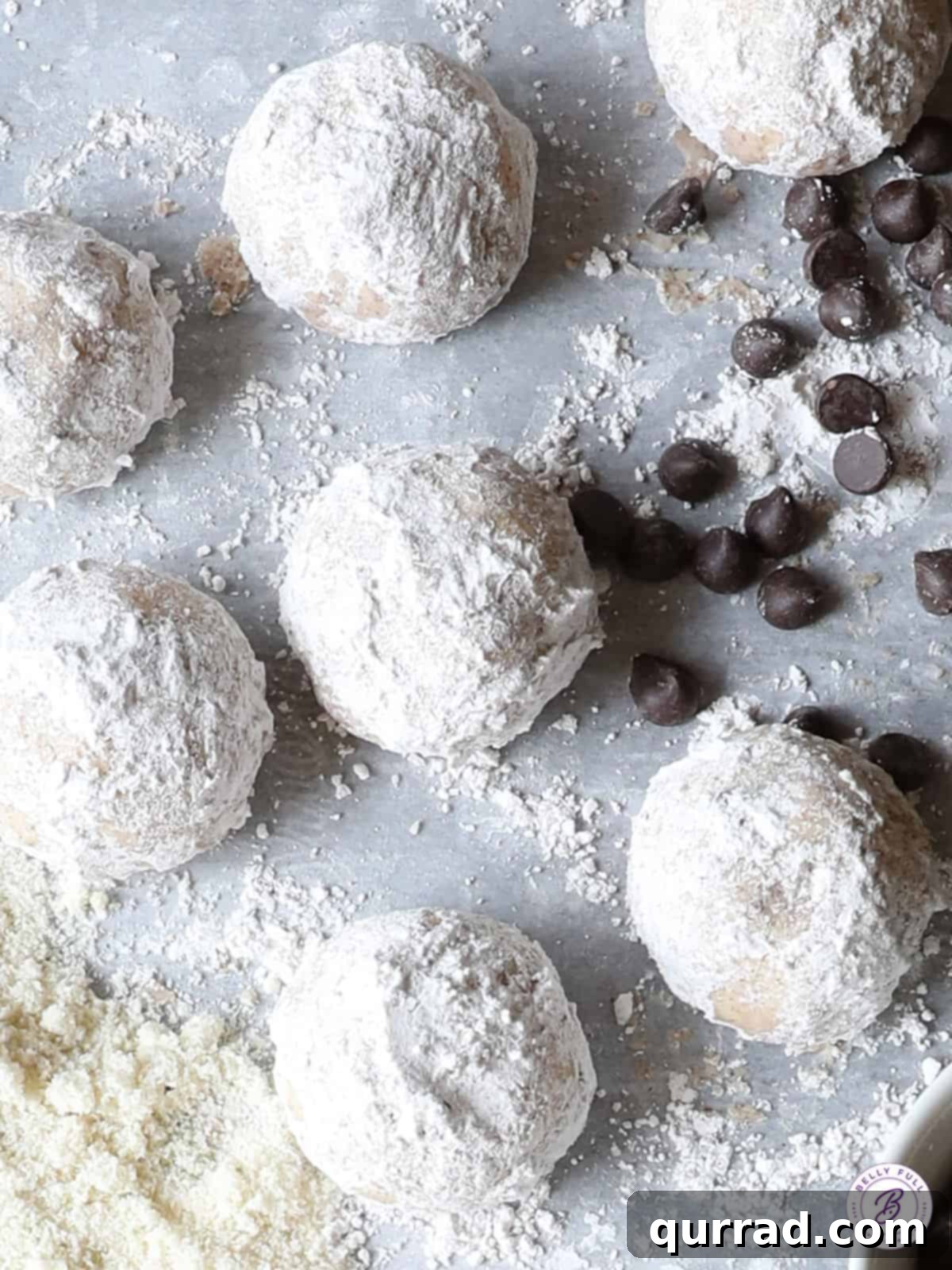 Snowball cookies cooling on parchment paper on a baking sheet, ready for their second dusting of spiced powdered sugar.