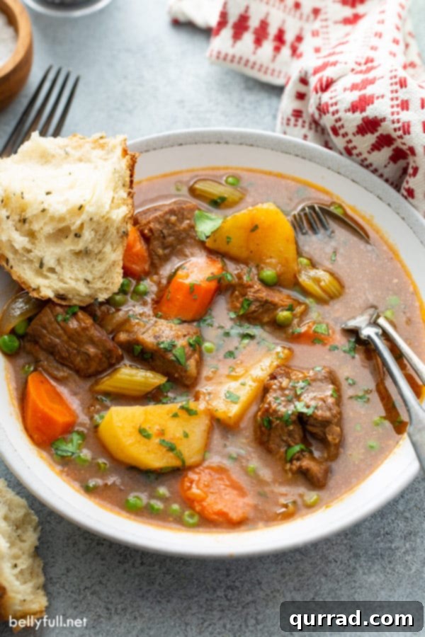 Rich beef soup served in a bowl with a piece of crusty bread, ready to be enjoyed.