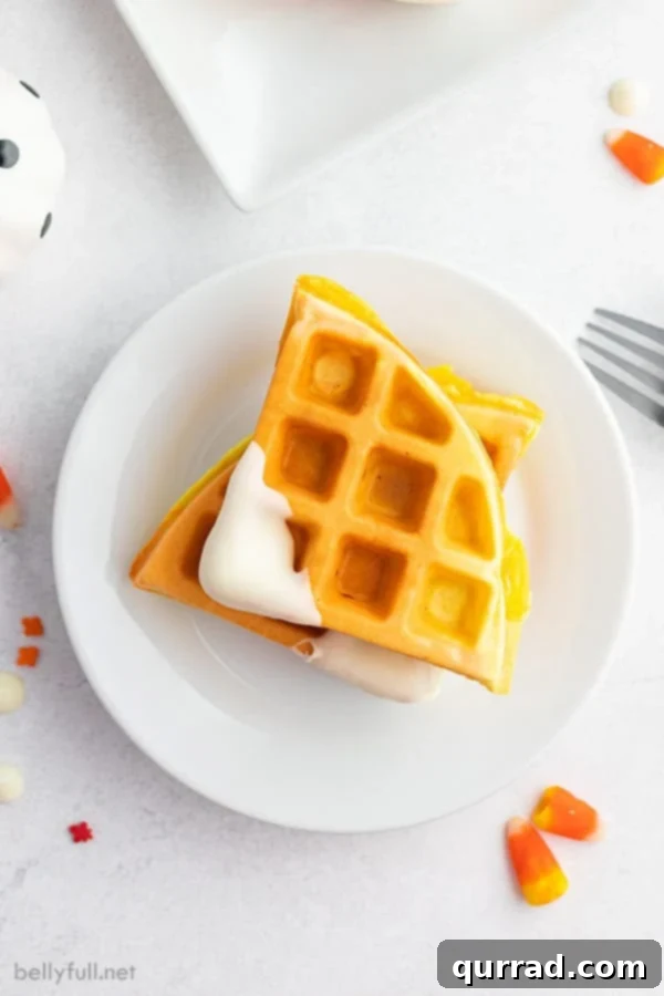 Individual Candy Corn Waffle triangles, perfectly colored in yellow and orange with white-dipped tips, artfully arranged on a white plate ready to be served.