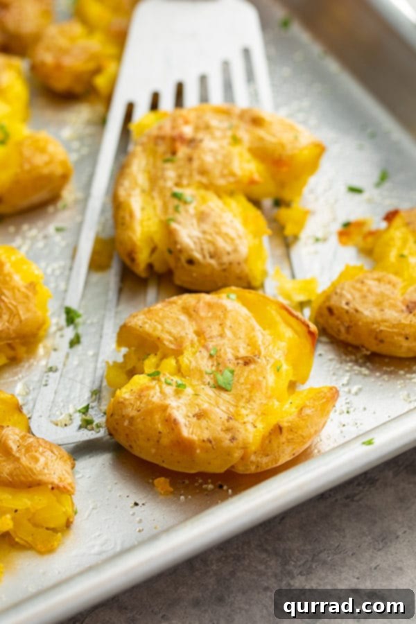 Golden Crispy Smashed Potatoes 5 A single roasted smashed potato being lifted on a wire spatula, highlighting its golden-brown texture.