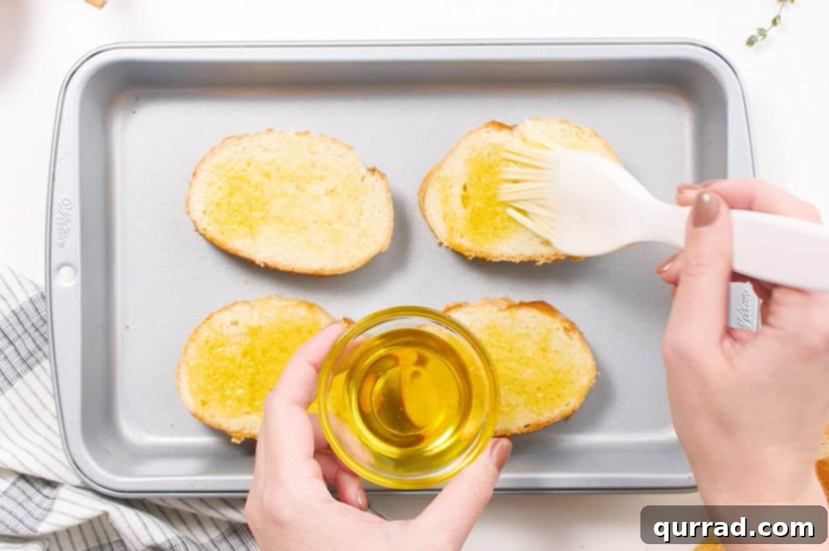 olive oil being brushed on french bread slices