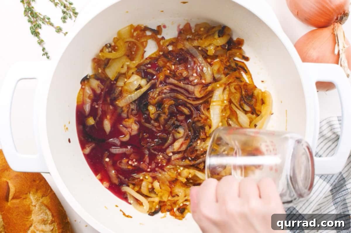 red wine being added to caramelized onions