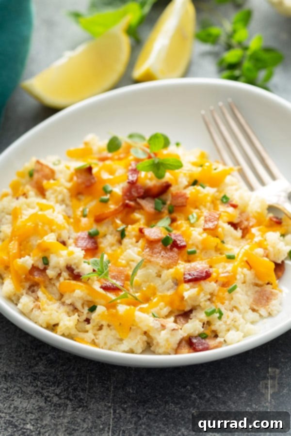 Ultimate Loaded Cauliflower Bake 5 A single serving of cauliflower mash garnished with crispy bacon crumbles on a white plate, ready to be enjoyed.