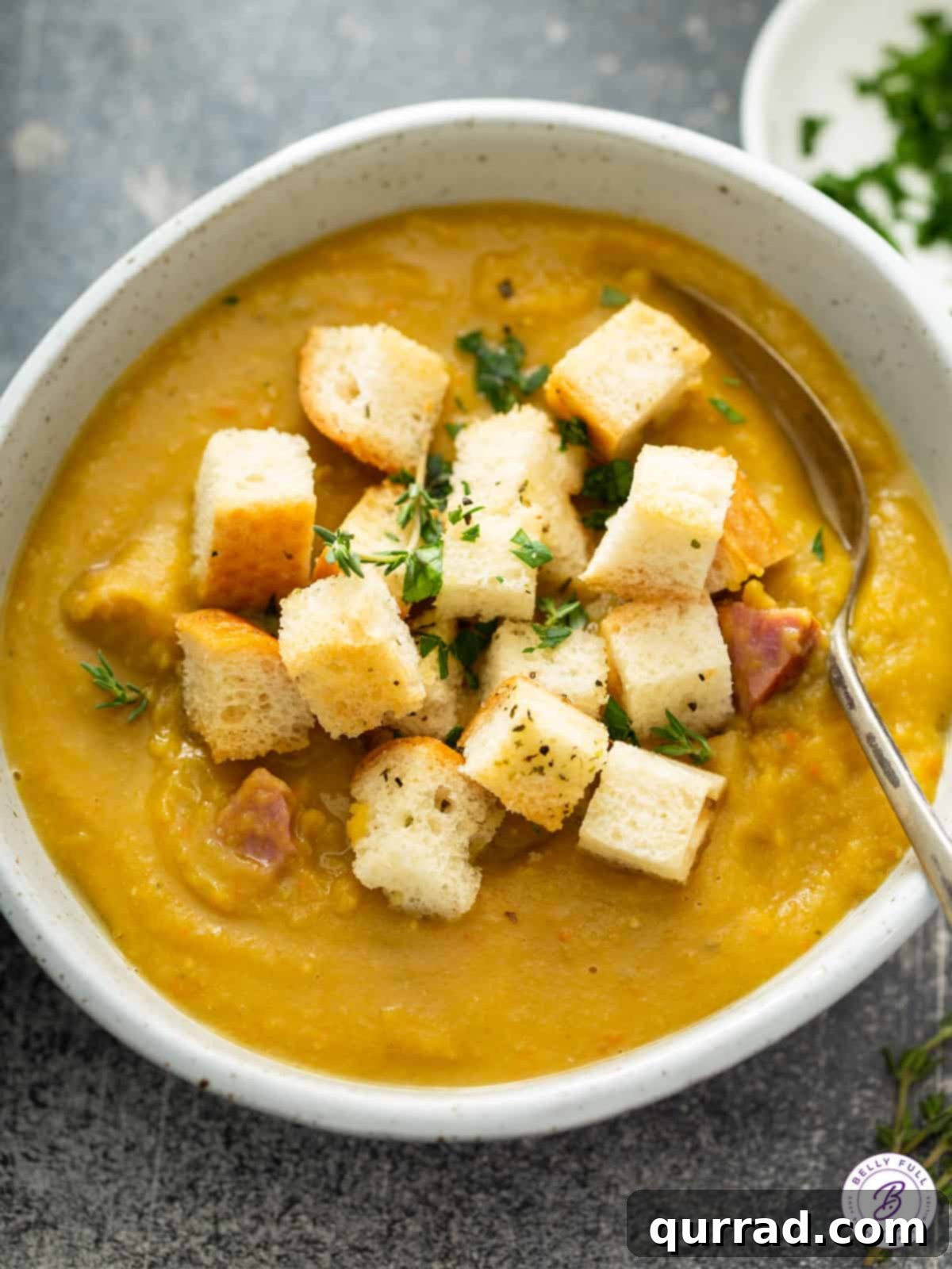 Emerald Comfort Soup 2 Overhead close-up bowl of creamy split pea soup with golden croutons and fresh herbs