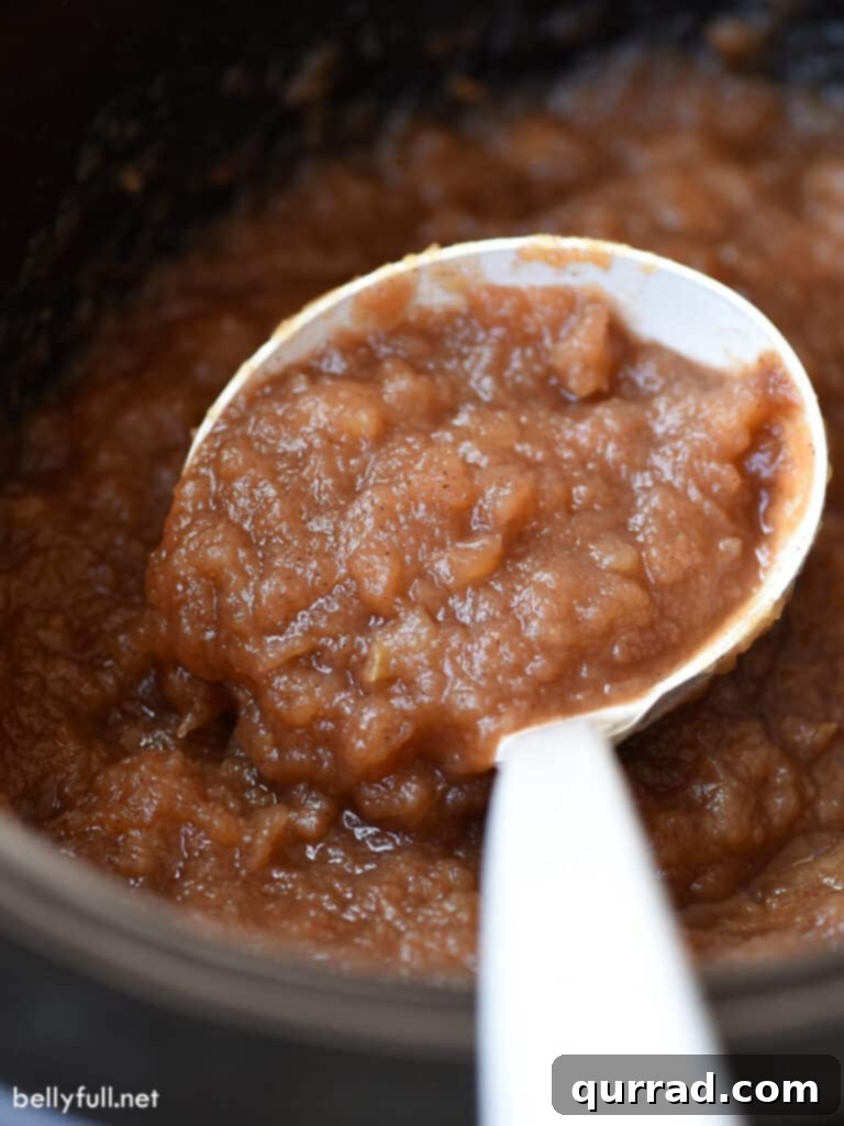 Apple Bliss from Scratch 2 A large scoop of freshly made homemade applesauce on a white ladle, ready to be served.