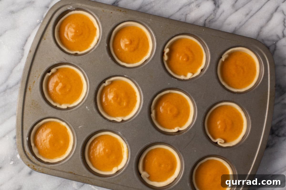 Bite-sized Pumpkin Delights 8 Mini pies in muffin tins filled with pumpkin pie filling, ready for baking.