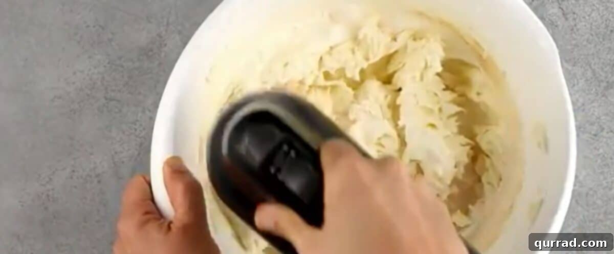 Decadent Oreo Cheesecake 5 Mixing the creamy cheesecake filling ingredients in a stand mixer, demonstrating the smooth texture.