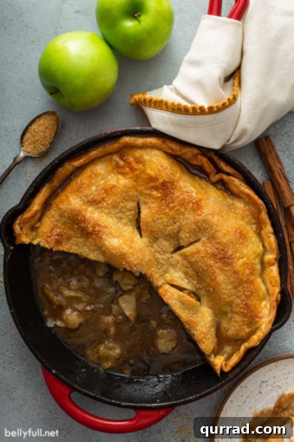 Overhead view of a baked skillet apple pie with a slice removed, revealing the tender apple filling and gooey caramel