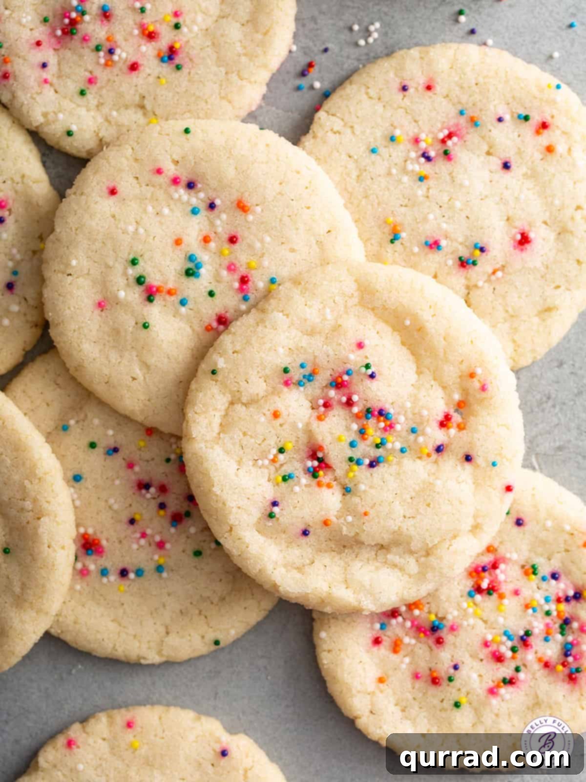 Effortless Sugar Cookies 2 Overhead shot of a pile of golden-brown 3-ingredient sugar cookies with vibrant rainbow sprinkles, beautifully arranged and ready to be enjoyed.