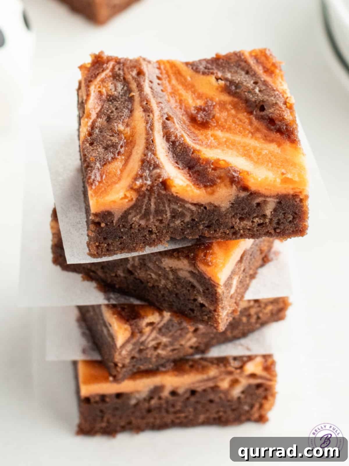 A tantalizing stack of four Halloween brownies, showcasing their rich chocolate base and vibrant orange swirl, ready to be devoured.
