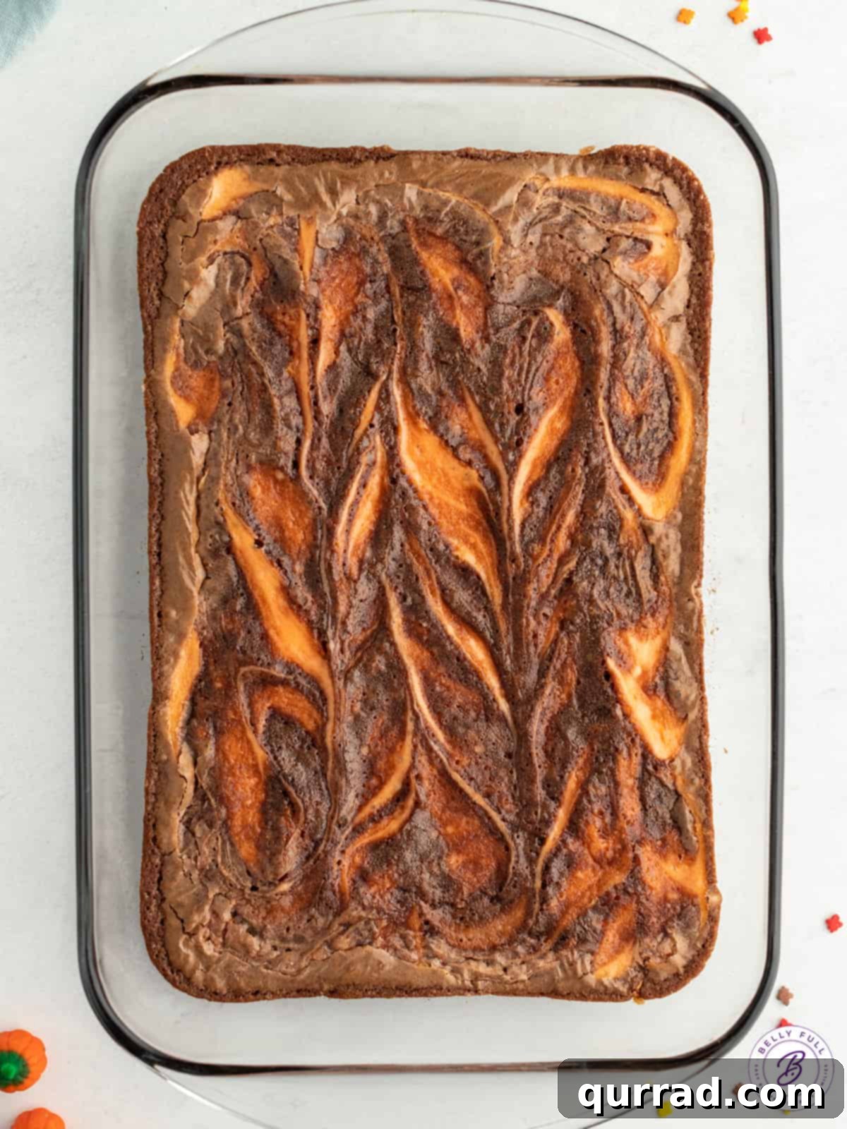 A close-up shot of an uncut pan of Halloween brownies, featuring the mesmerizing orange swirl against the dark chocolate, ready for chilling.