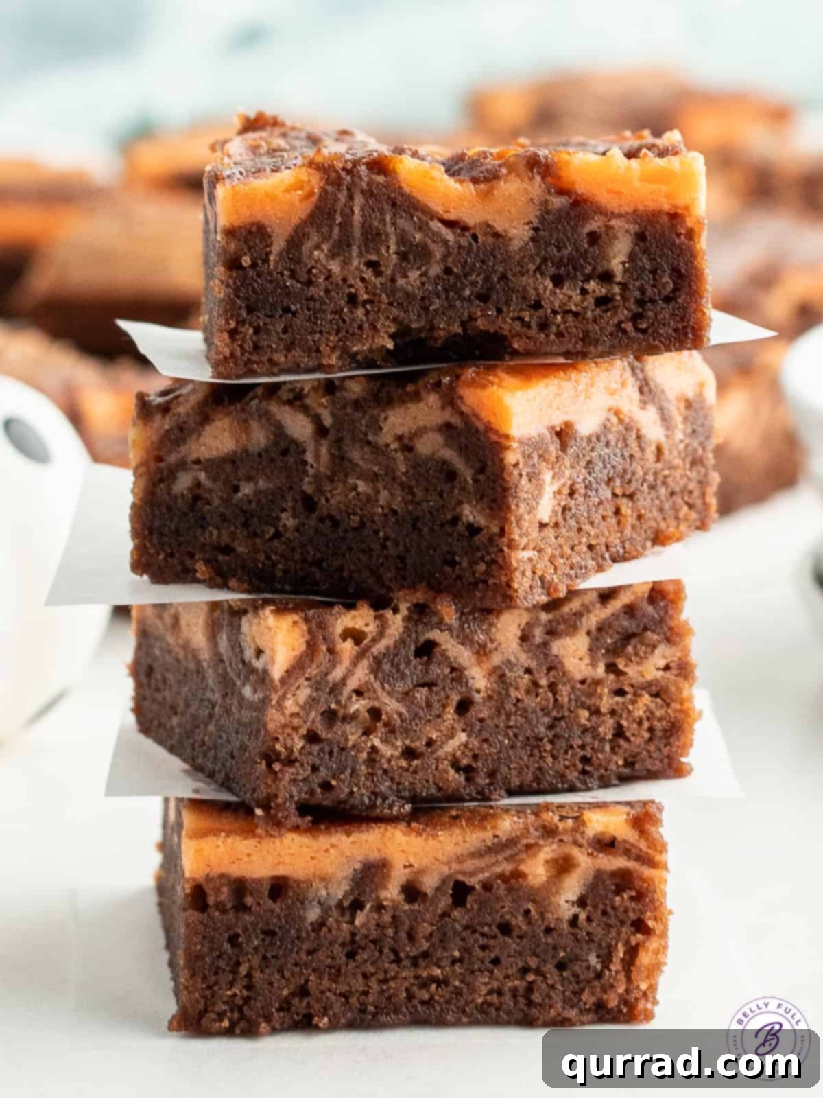 A delightful stack of four Halloween brownies, each one a perfect square, revealing the contrasting chocolate and orange layers.
