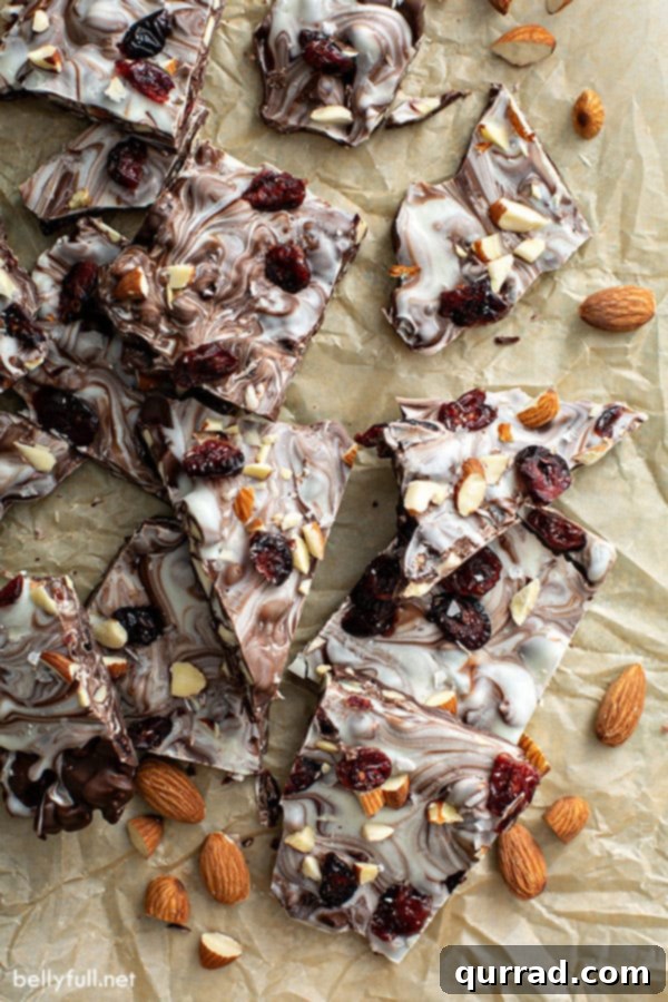 Sweet-Tart Cranberry Almond Chocolate Bark 4 A pile of chocolate bark pieces resting on brown parchment paper, ready to be served or packaged.