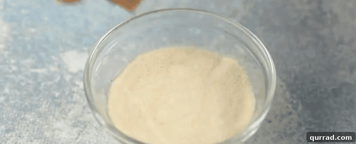 Velvety Vanilla Panna Cotta Treat 4 Gelatin powder being sprinkled over cold water in a small glass bowl, beginning the blooming process.