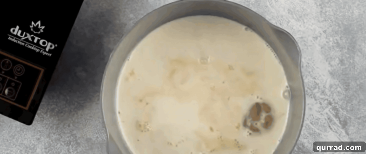 Velvety Vanilla Panna Cotta Treat 6 A whisk stirring bloomed gelatin and vanilla extract into the warm cream mixture in a saucepan.