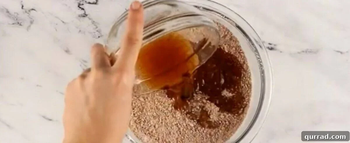 The rum and honey mixture being poured into the bowl containing the dry cookie and pecan mixture.