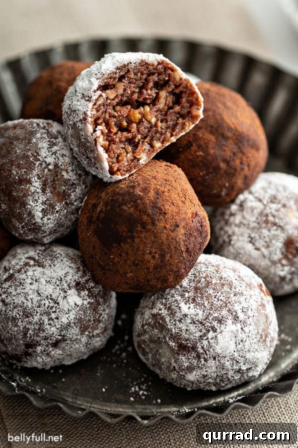 A rum ball with a bite taken out, resting on top of other whole rum balls, showing its rich, moist interior.