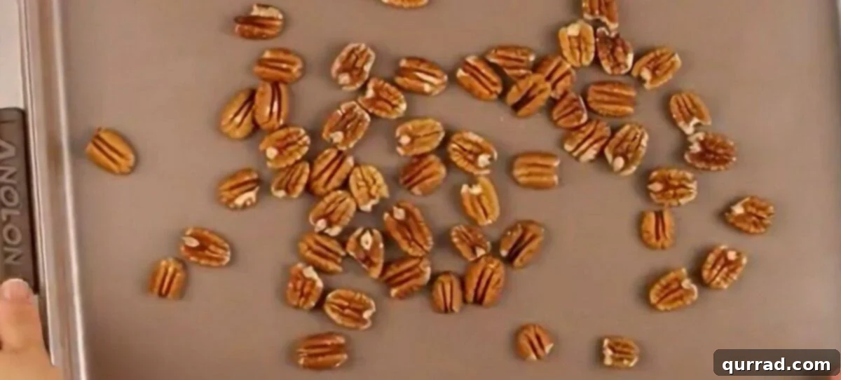 Pecans spread out evenly on a cookie sheet, ready for toasting.
