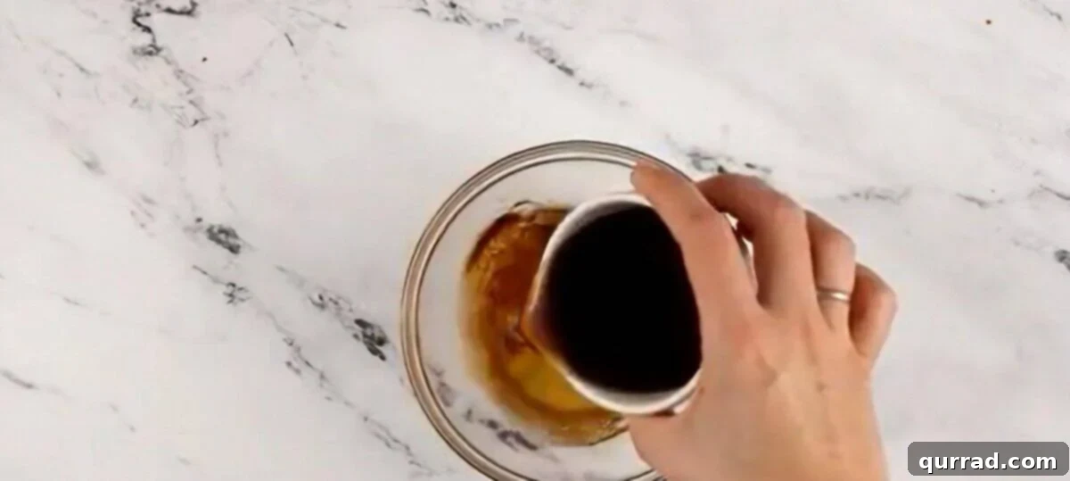 A small bowl showing spiced dark rum and honey being whisked together until fully combined.