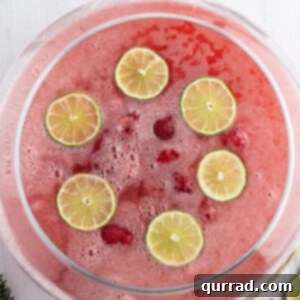 overhead of Christmas punch in punch bowl with lime slices and frozen raspberries