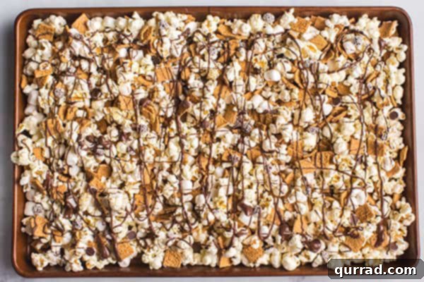 popcorn snack mix drizzled with chocolate on baking sheet