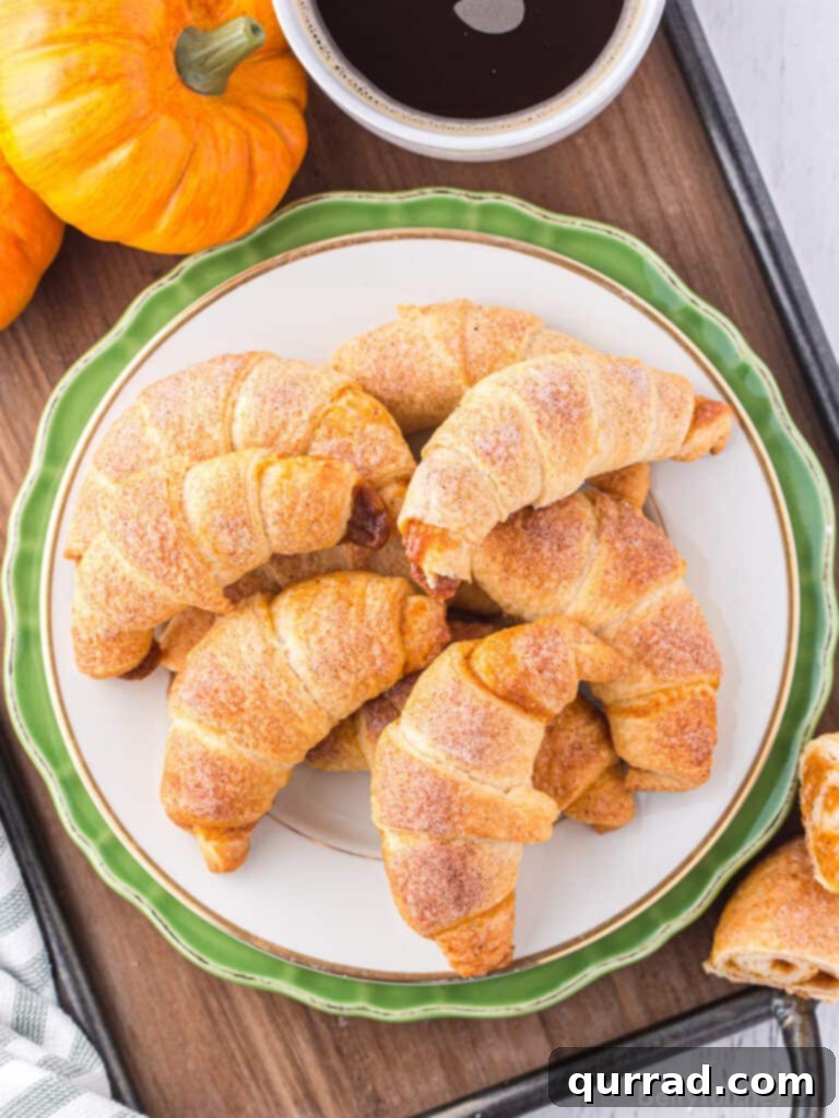 pile of baked crescent rolls on green rimmed plate