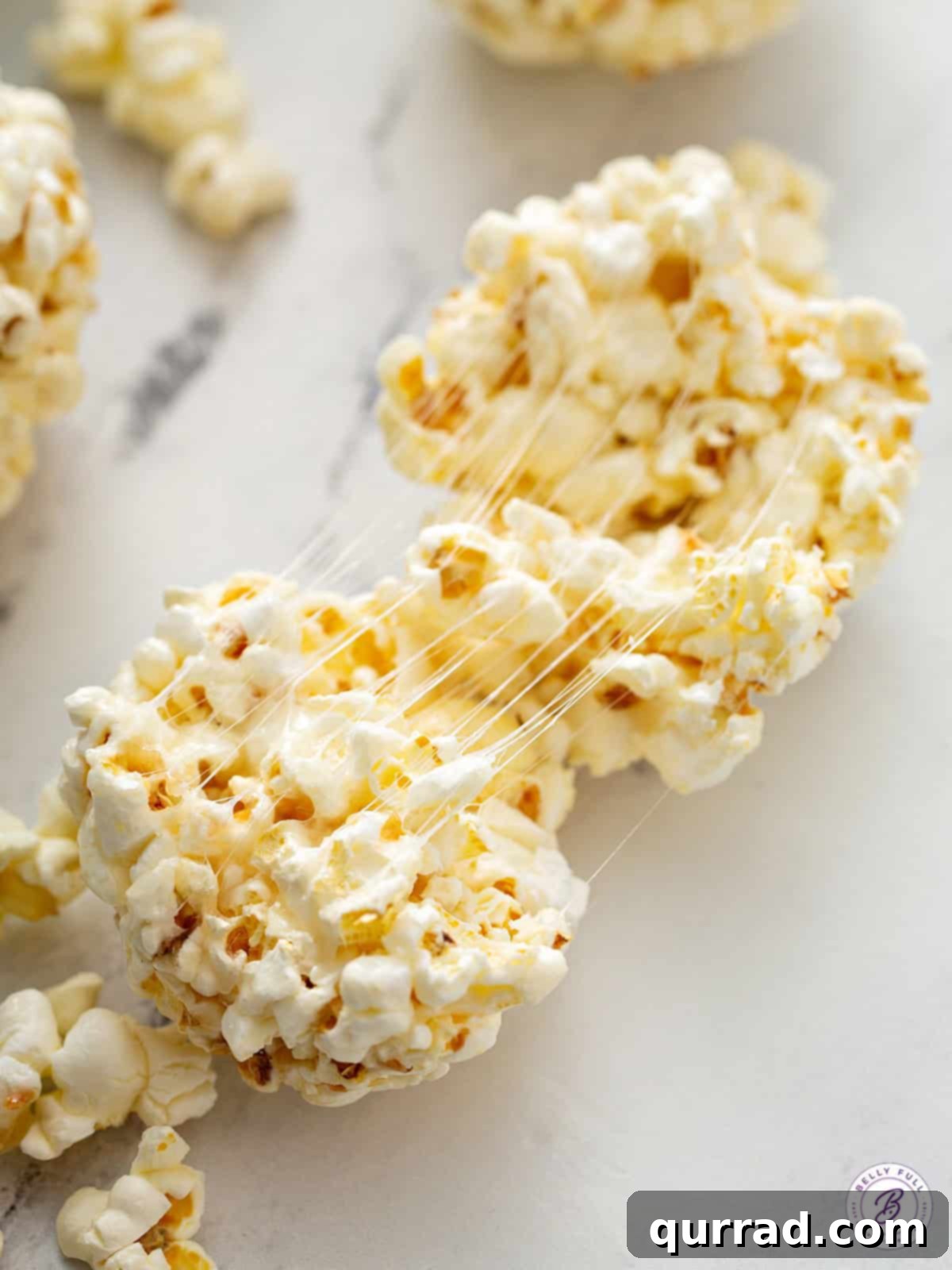 Sweet Popcorn Bites 4 A popcorn ball gently pulled open, revealing gooey marshmallow strands within.