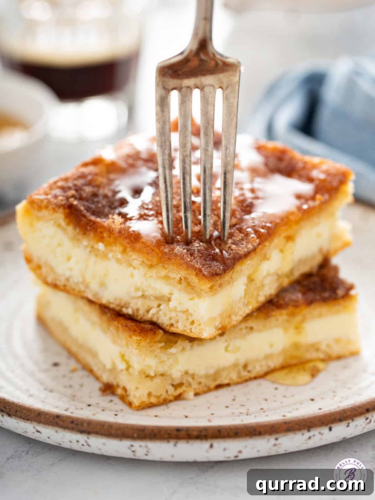 Honey Kissed Sopapilla Cheesecake 5 Two stacked Sopapilla Cheesecake bars with a fork pressing down on the top one, showing the creamy filling