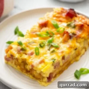A perfectly baked slice of hash brown egg casserole on a white plate, showcasing golden edges and a fluffy interior.