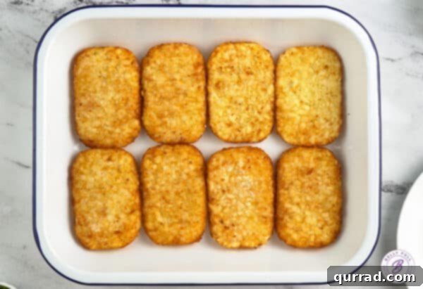 Eight frozen hash brown patties perfectly arranged in a single layer at the bottom of a casserole dish.