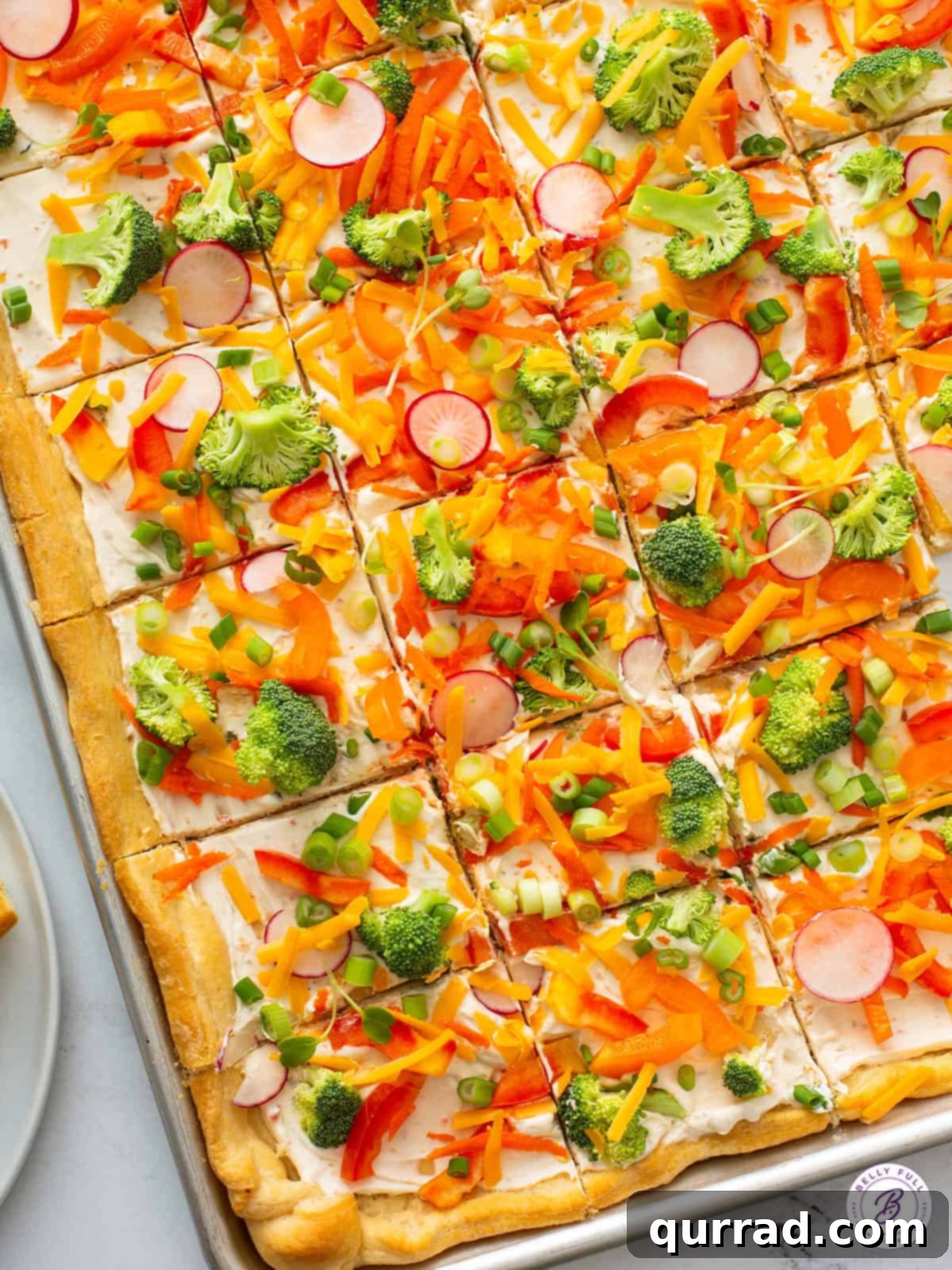 Overhead shot of a full sheet tray of sliced cold veggie pizza, showcasing its vibrant colors and delicious appeal, ready for serving.