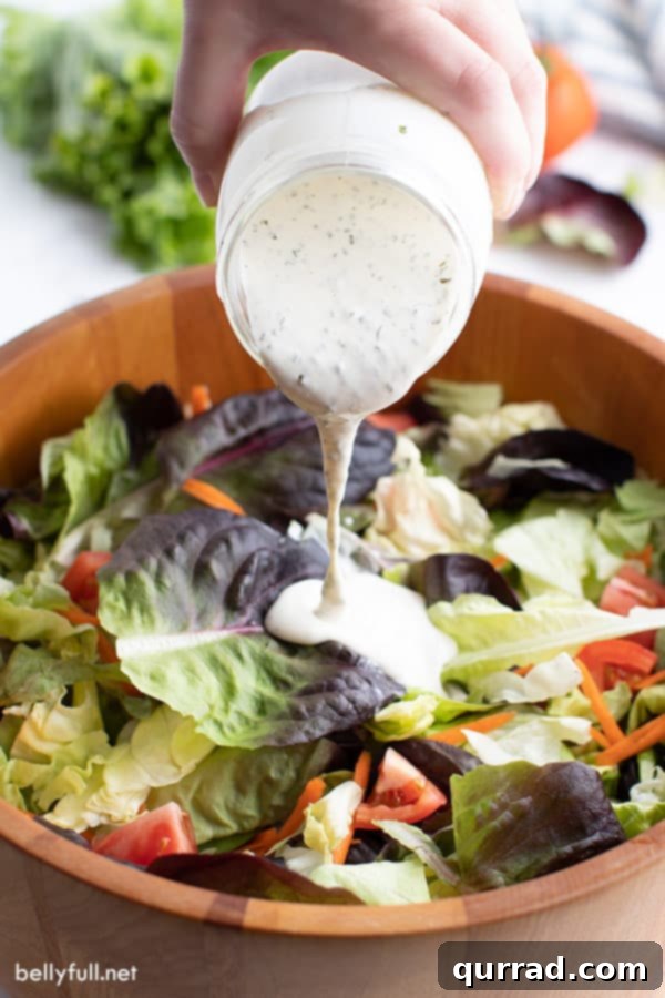 ranch dressing pouring out of jar onto salad