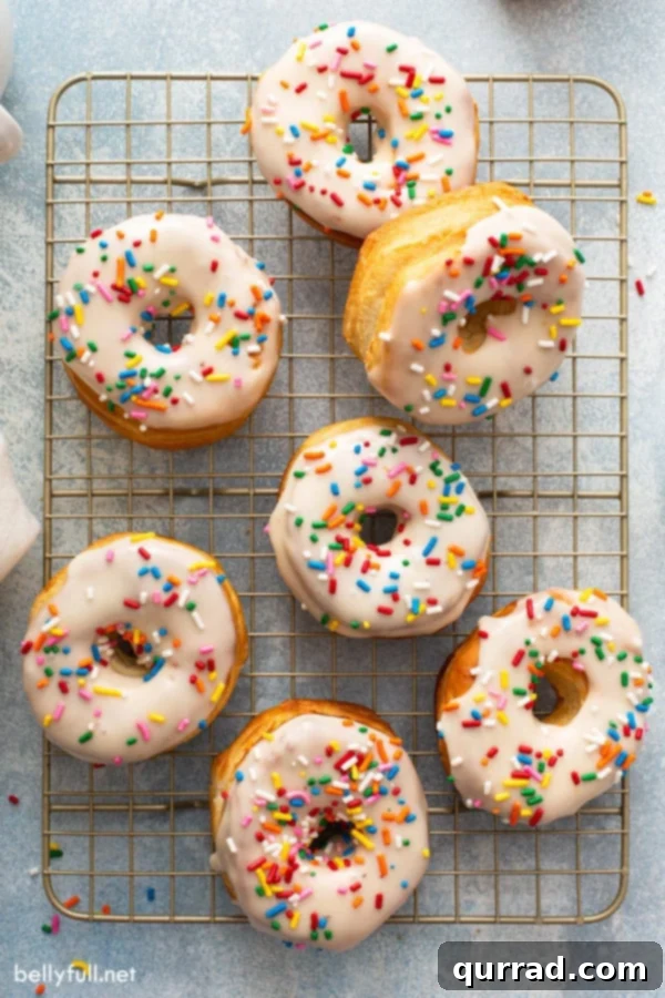 Quick Air Fryer Donut Delight 9 Overhead of 7 donuts on cooling rack with glaze and sprinkles.