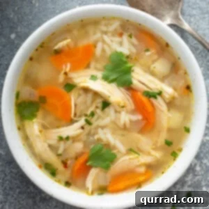 Golden Chicken Rice Elixir 6 A comforting overhead view of a bowl of homemade chicken and rice soup, brimming with tender chicken, perfectly cooked white rice, and vibrant carrots, garnished with fresh parsley.