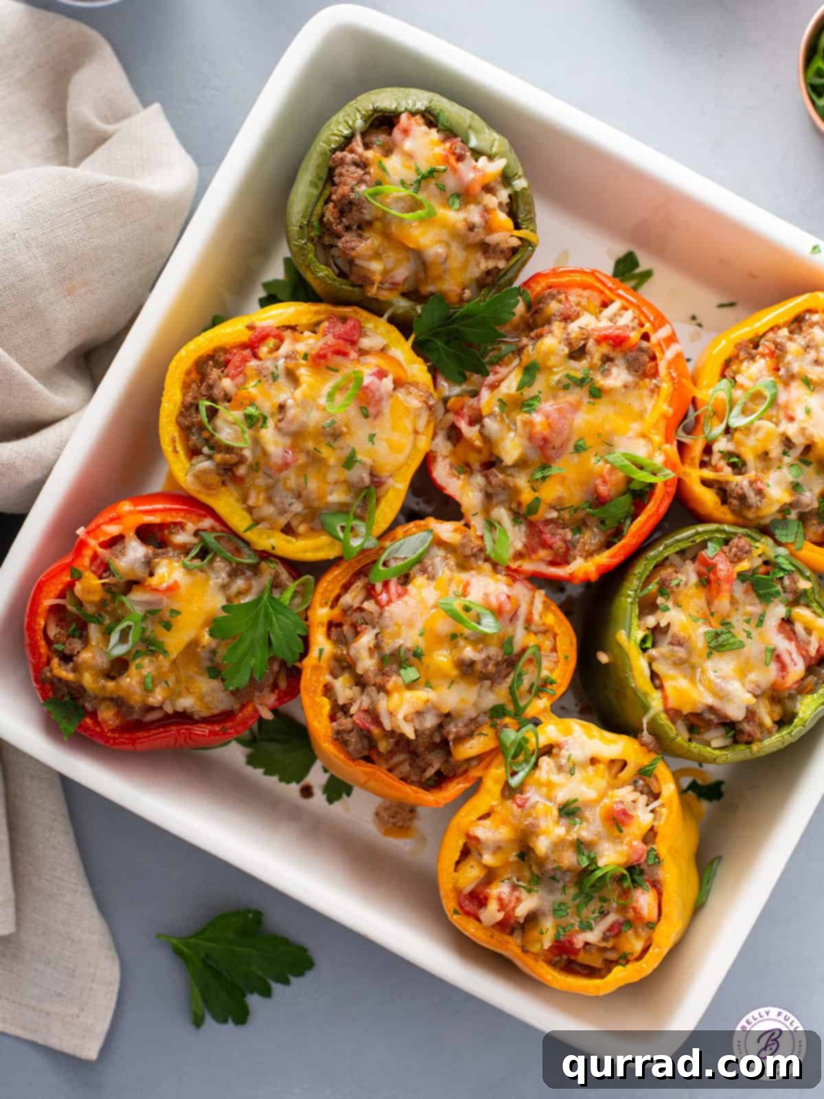 Flavor-Packed Peppers 2 Fırında eritilmiş peynirli dolgulu biberlerin bir güveç kabında üstten görünümü, canlı renkleri ve altın rengi kabukları vurgulanıyor.