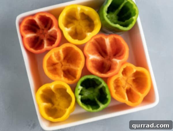 Flavor-Packed Peppers 5 İç harcı için hazır, içi boşaltılmış yeşil, kırmızı, sarı ve turuncu dolmalık biberler güveç kabına yerleştirilmiş.