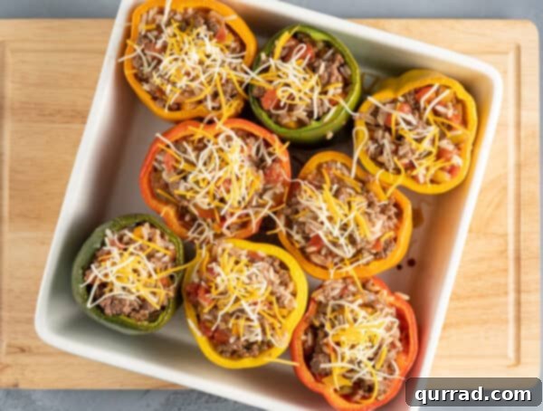 Flavor-Packed Peppers 8 Fırında pişirilmeden önce güveç kabındaki dolgulu dolmalık biberlerin üstten görünümü, peynirle kaplanmış.