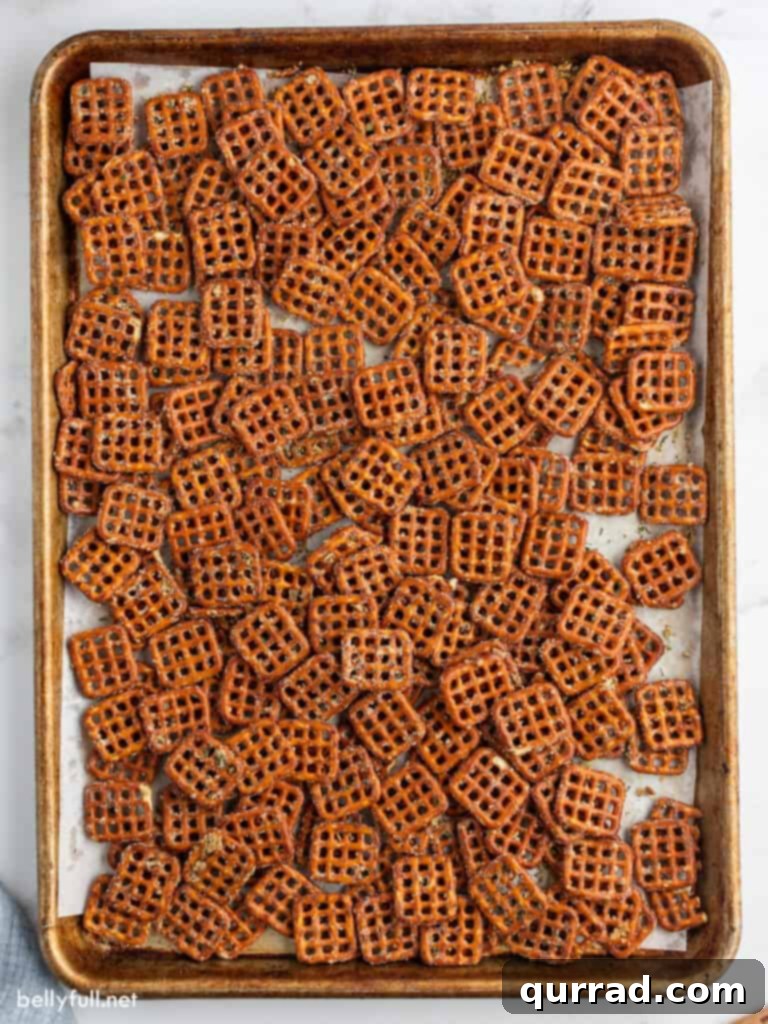 Zesty Ranch Pretzels 3 A single, even layer of seasoned pretzels spread out on a baking sheet, ready to be baked to perfection.