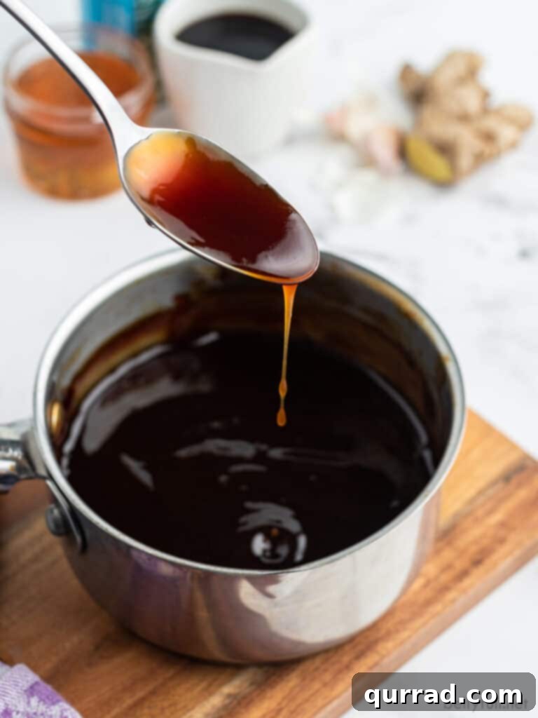 Teriyaki Perfection: Made From Scratch 4 Thick, glossy Teriyaki sauce dripping from a spoon into a saucepan, showcasing its perfect consistency.