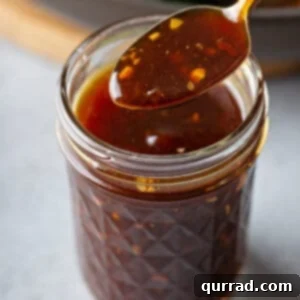 Stir Fry Sauce on a spoon over a mason jar, showcasing its smooth texture and rich color.