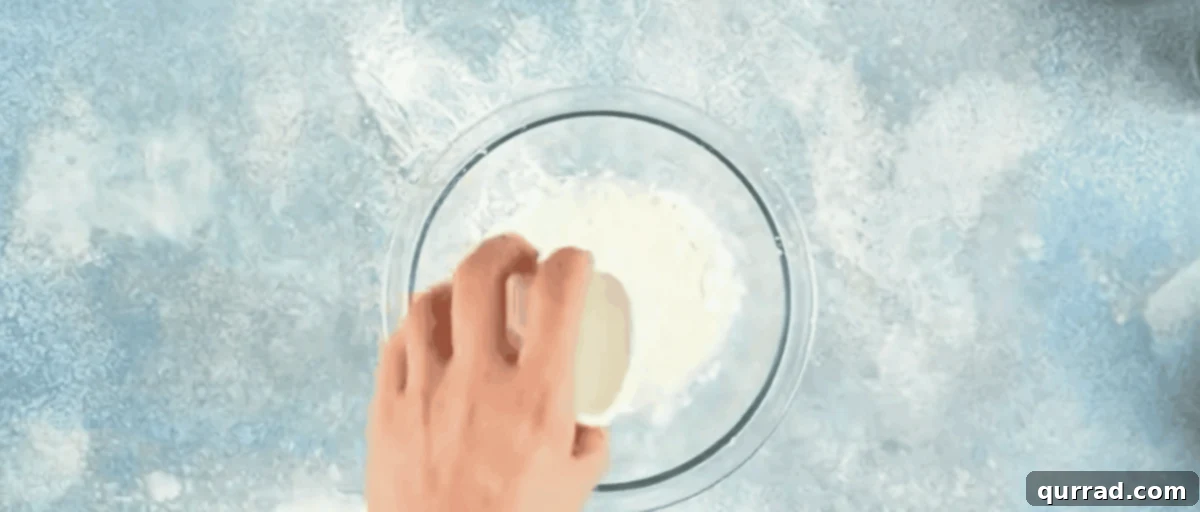 Essential Stir Fry Base 4 A hand combining cornstarch and water in a clear glass bowl with a small whisk, creating a smooth slurry.