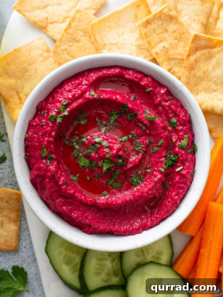 Vibrant Beetroot Hummus 3 overhead magenta hummus in white dish surrounded by veggie sticks and pita crackers