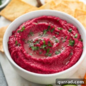 side angle homemade beet hummus on white serving bowl