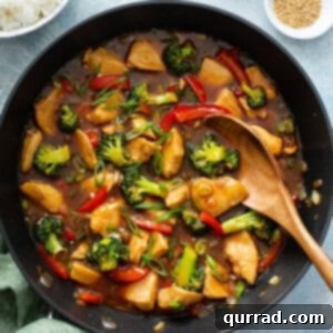 chicken stir fry in skillet with wooden spoon