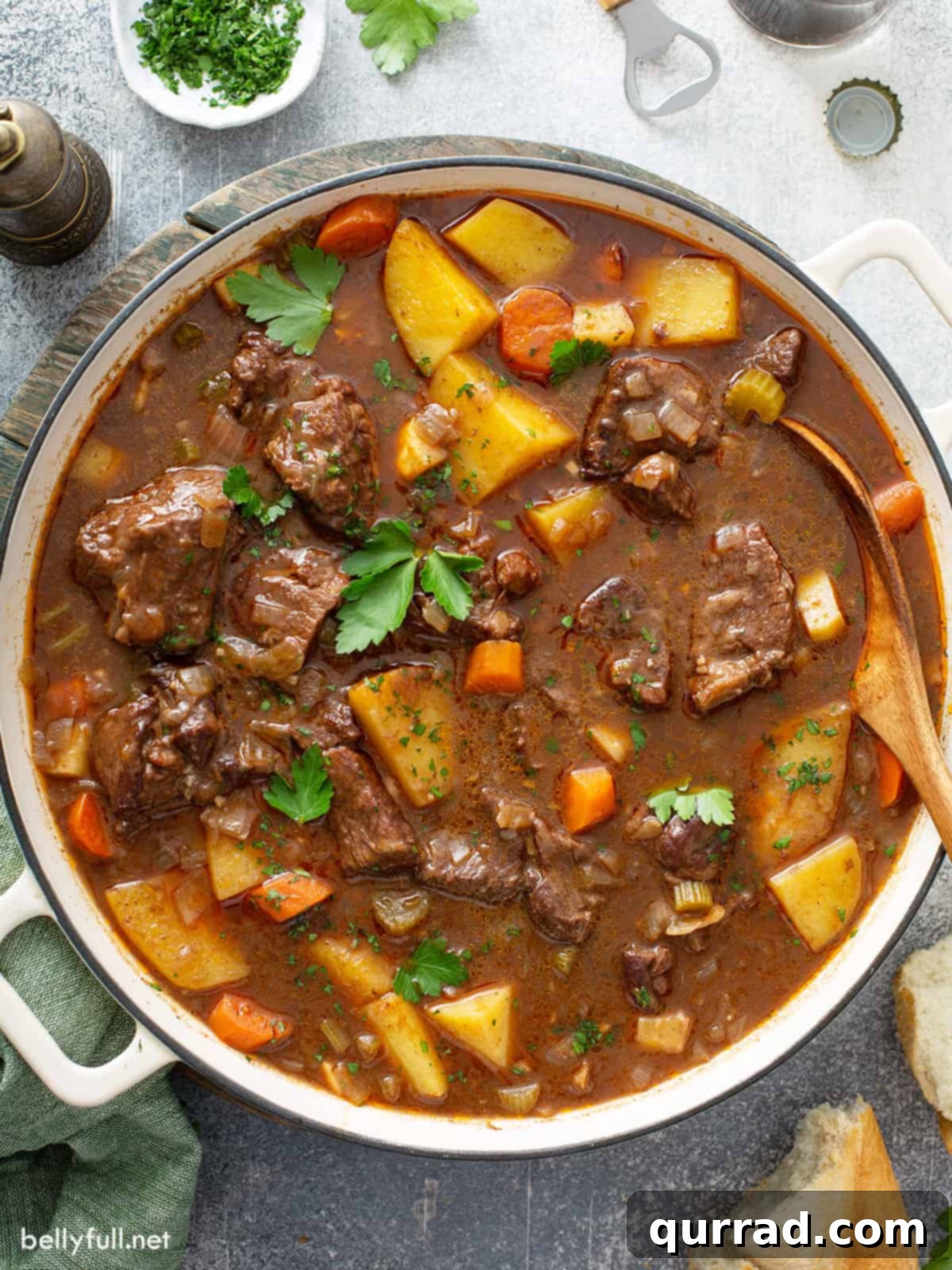 Hearty Irish Beef Stew 2 Overhead view of a white Dutch oven pot filled with Irish beef stew, garnished with fresh herbs.