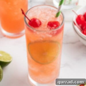 A glass of Cherry Limeade, garnished with lime and cherries.