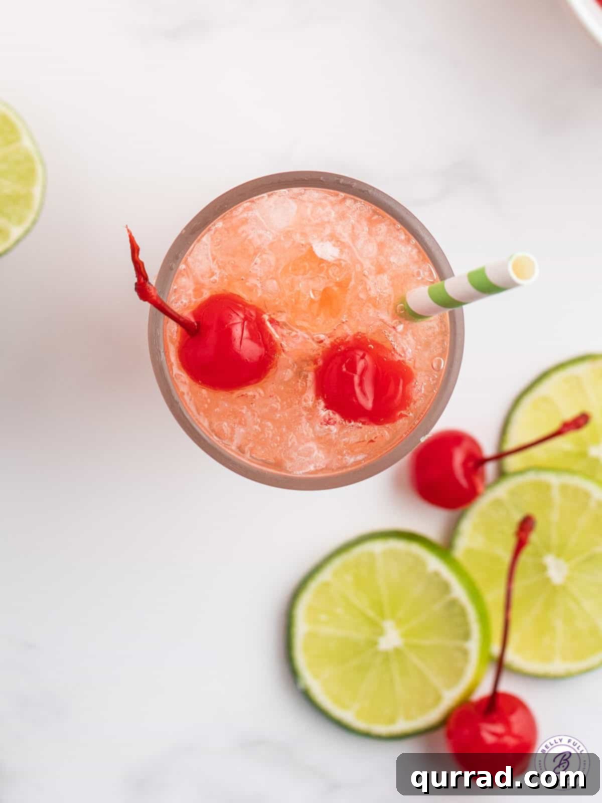 Sparkling Cherry Limeade 5 An overhead shot of a glass of Cherry Limeade with a straw, garnished with lime and cherries, ready to be enjoyed.