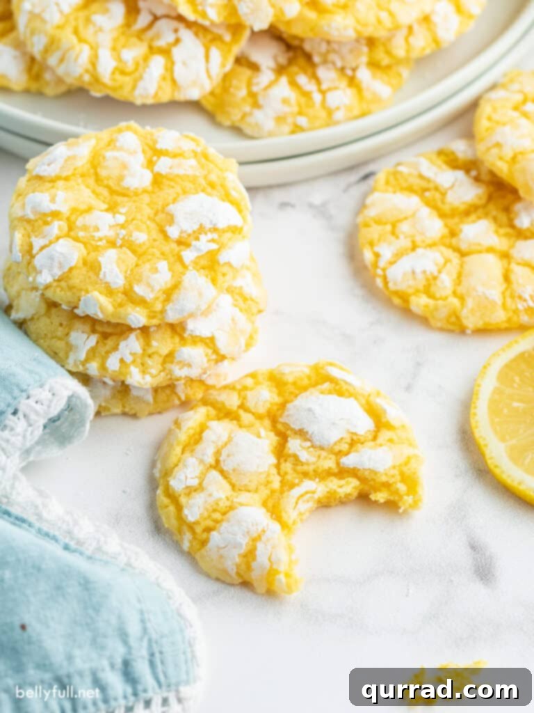 A close-up of a Lemon Crinkle Cookie with a bite taken out, revealing its soft, tender interior and the bright lemon zest.
